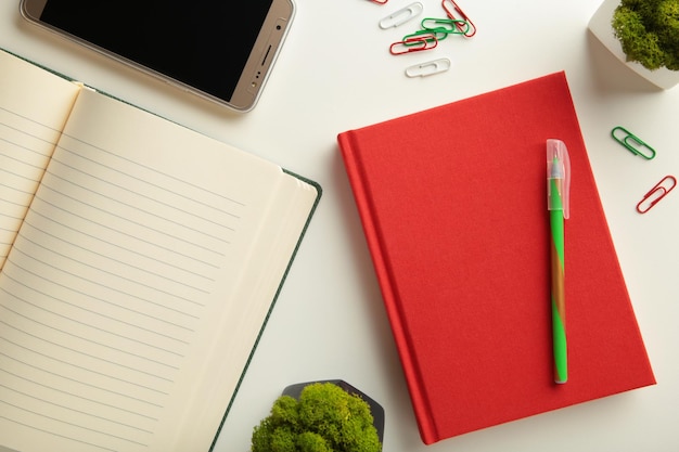 Red notebook with smartphone on grey background.