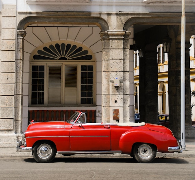 Фото Красная старая старинная машина перед зданием в гаване, куба