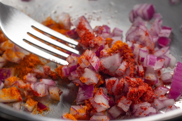 Red onion turmeric and saffron seasoning in a stainless steel pot with a fork