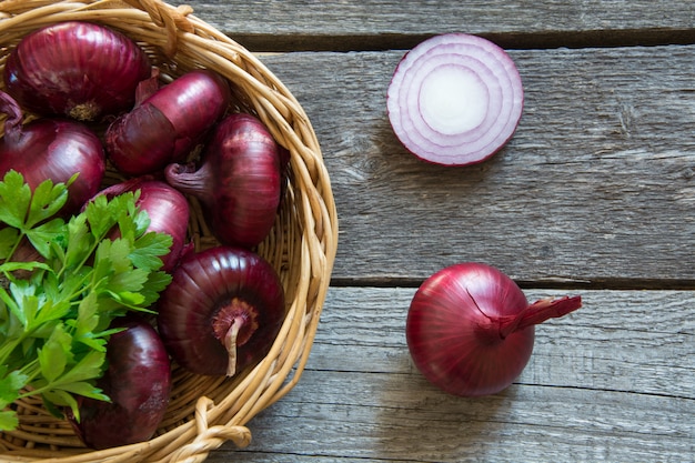 Red onions in basket on rustic wooden board