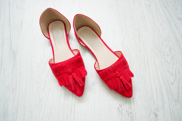 Red open shoes on a light wooden background.