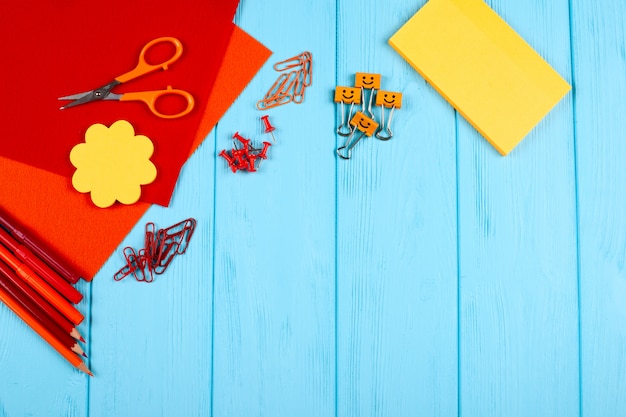 Red and orange stationery on blue wooden background.