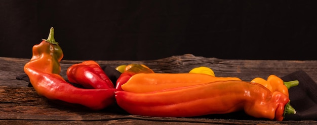 Red orange and yellow long peppers on an old rustic wooden table