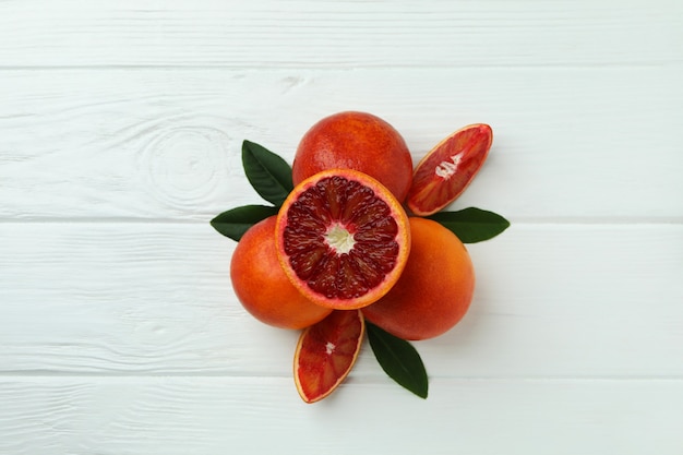 Red oranges and leaves on white wooden table