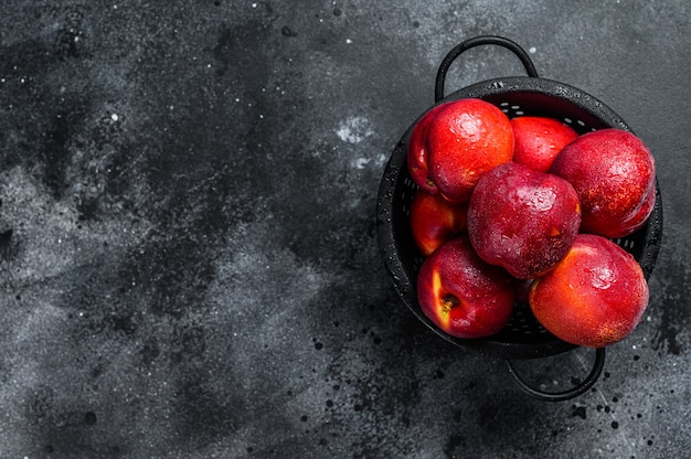 Red organic nectarines in a colander.