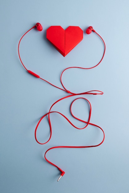 Red origami heart with headphones on blue table