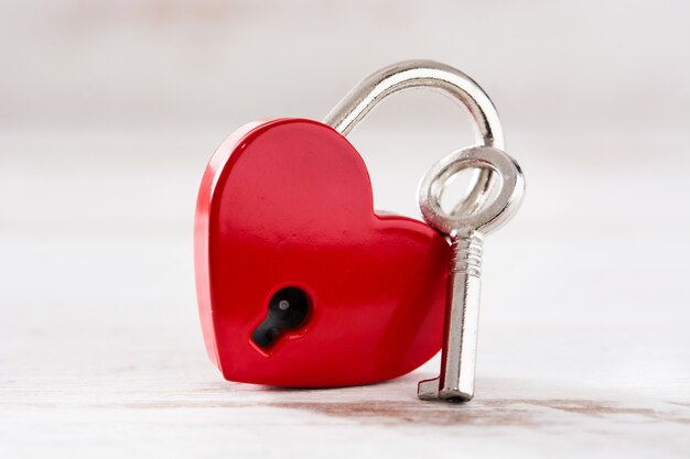 Red padlock hearts with key on white wooden background