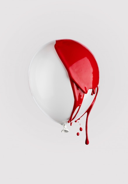 Red paint dripping on a white balloon. Creative trendy minimal concept.