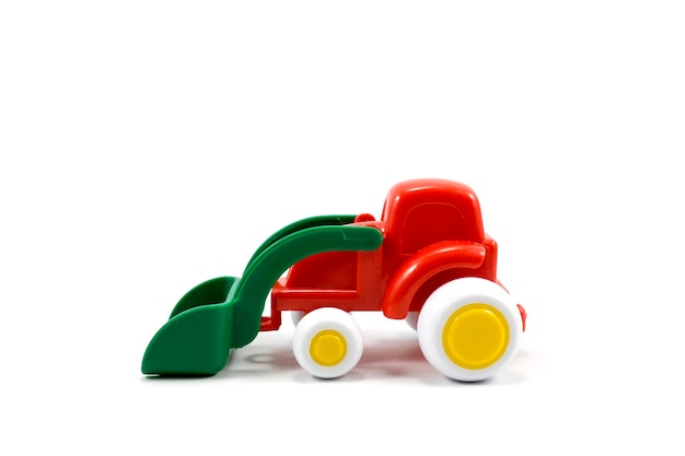 Red paint plastic toy bulldozer with green universal blade isolated on white