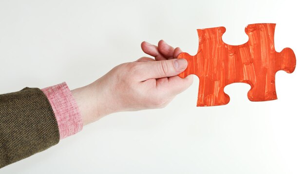 Red painted puzzle piece in male hand