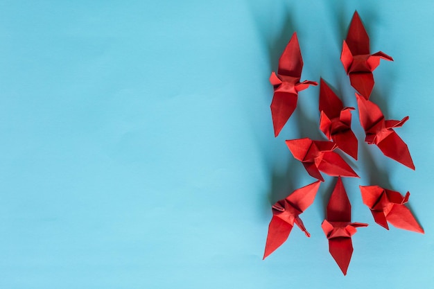 Photo red paper bird on a blue background,origami, paper crane, paper, toy, japan