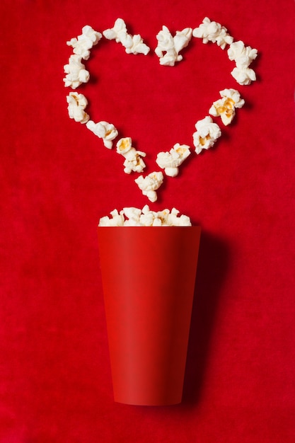 Red paper cup with scattered popcorn shaped heart on red