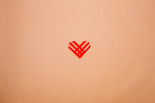 Red paper heart on beige paper background Giving Tuesday