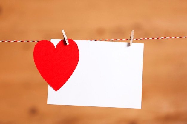 Red paper heart and blank white label pegged to a string