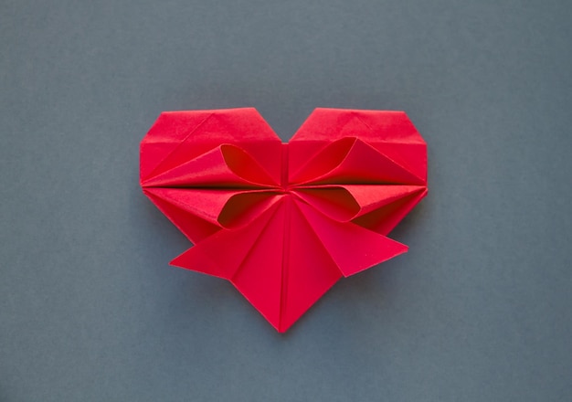 Фото Оригами сердце из красной бумаги, изолированные на сером фоне