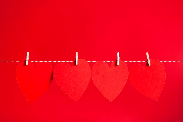 Red paper heart pegged to a string against a red background