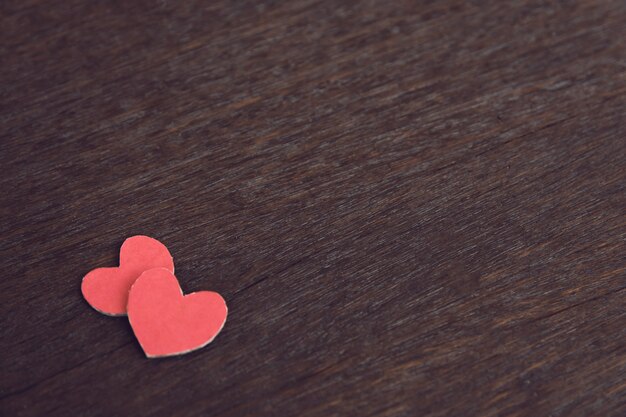 Red paper hearts on dark wooden table