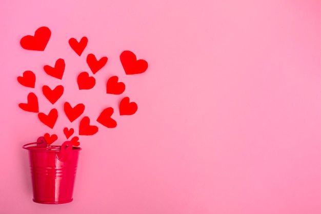 Red paper hearts flying out of a bottle. Valentine on pink background with copy space