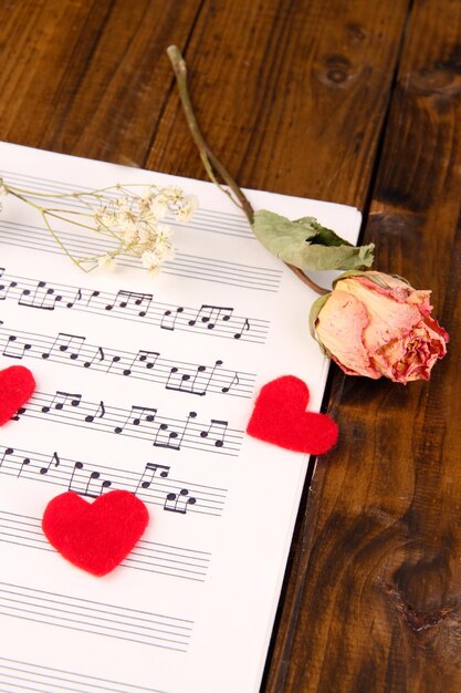 Photo red paper hearts on music book closeup on wooden background