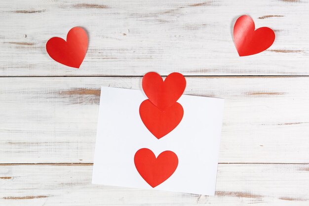 Red paper hearts printed on paper on a white wooden background Declaration of love valentine's day concept