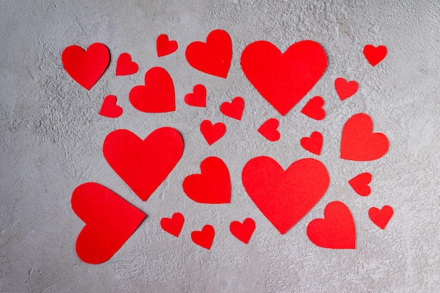 red paper hearts scattered over gray plaster