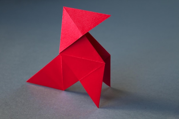 Red paper hen origami isolated on a grey background