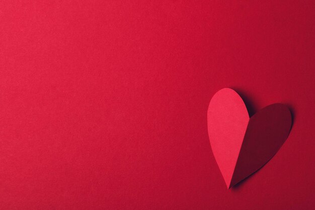 Red paper love heart on a plain red background Valentines day romance background