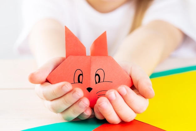 Red paper rabbit in the hands of a child