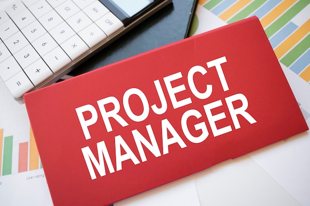 바탕 화면에 PROJECT MANAGER, 계산기 및 펜이라는 텍스트가 있는 빨간 종이 시트. 비즈니스 개념