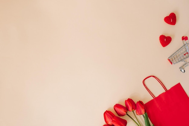 Red paper shopping bag a bouquet of tulips and a shopping cart Holiday discounts for Valentine's Day with copy space