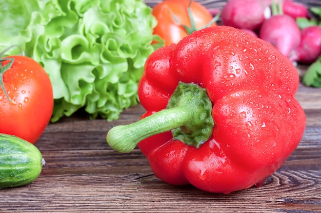 Red paprika on vegetables on brown wooden table