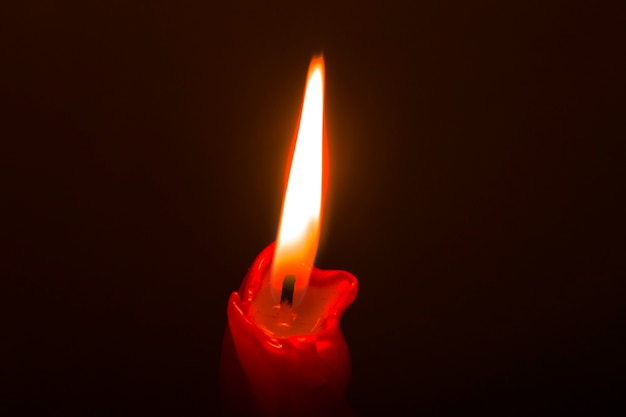 Red paraffin mournful commemorative thick candle burns on a black background close-up