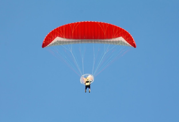 Red paragliding person on blue sky