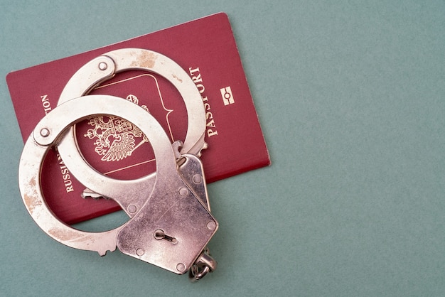 Red passport and handcuffs on a green background. Identity document of a person.