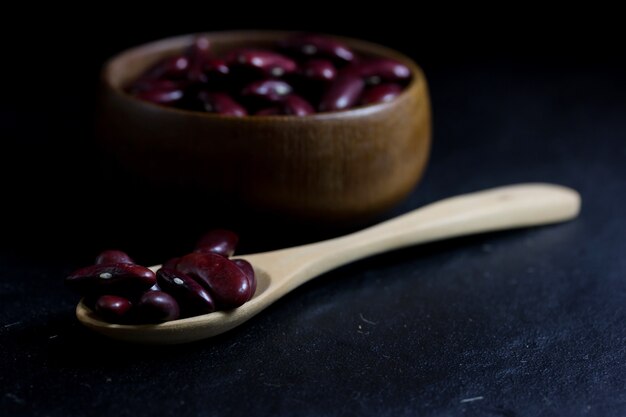 Red Peanut on Cup made of wood and spoon on black background