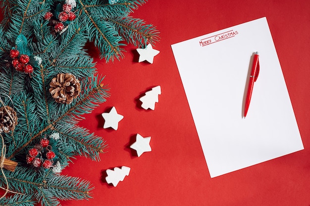 Red pen and notepad on red table decorated with a fir branch the background for the text