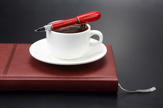 Red pen on a white Cup of black coffee
