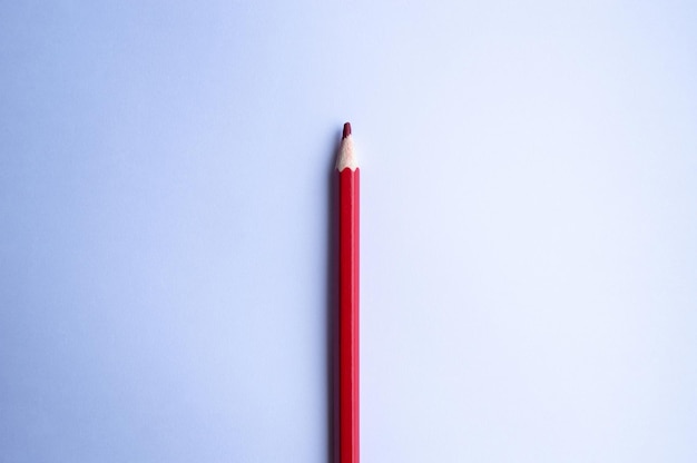 Red pencil lies on a blank sheet of white paper