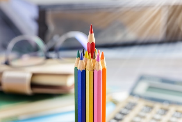 Red pencil standing out from a bunch of colored pencils 