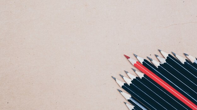 Red pencil standing out from crowd of plenty identical black fellows 