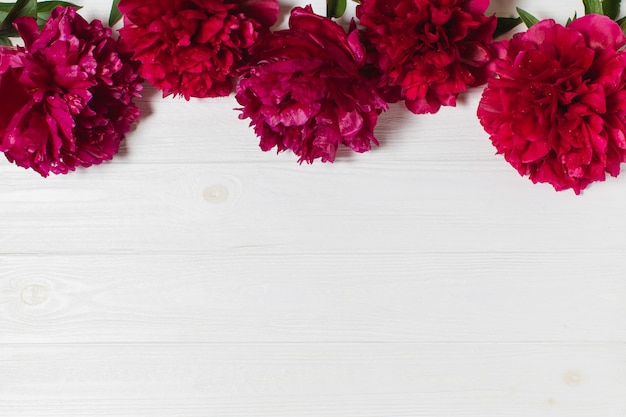 Red peonies on a white wooden table