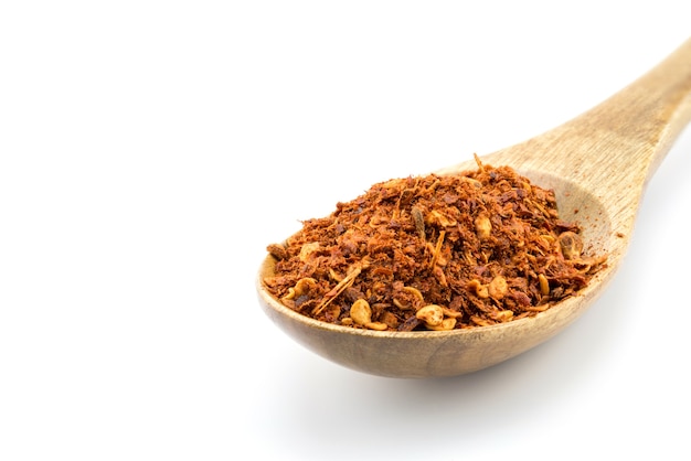 Red pepper flakes in wooden spoon on white background