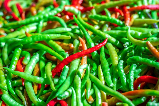 Red pepper on green peppers blurred background