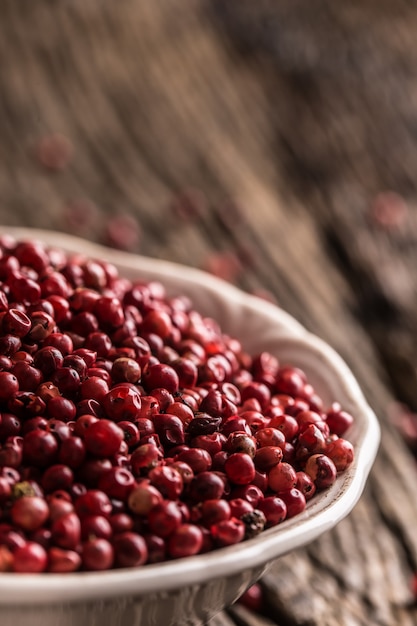 Red peppercorn in bowl on oak table.