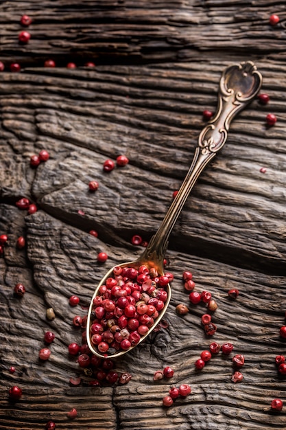 Red peppercorn on spoon on oak table.