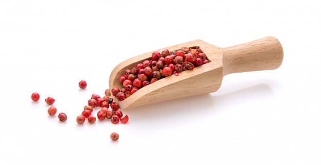 Red peppercorn in wood scoop on white wall