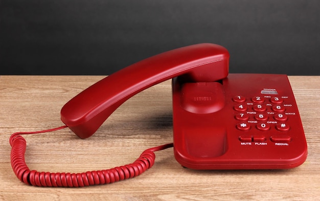 Photo red phone on wooden table on grey background