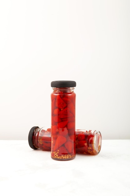 Red pickled mini chili peppers in glass jars Preserved pepper hot spice for meat or vegetarian salad