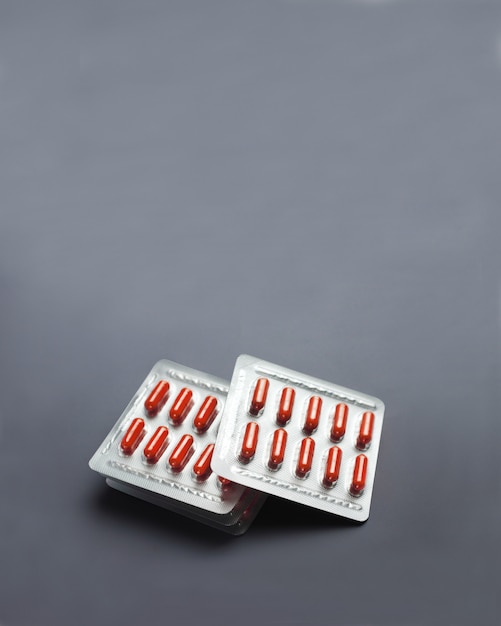 Photo red pill capsules in blister packs on gray surface