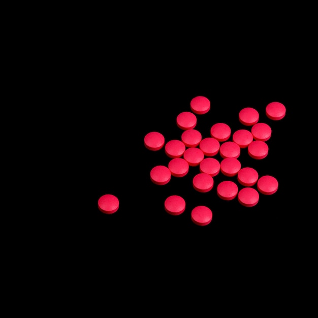 Красные таблетки разбросаны на черном фоне
